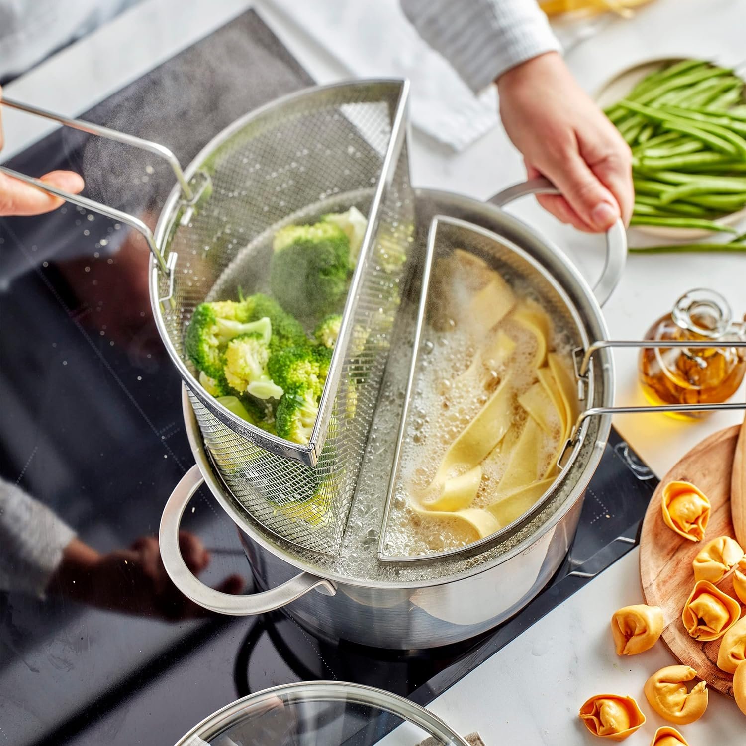Olla multiuso Demeyere Resto 7-en-1 de 8.5 qt con insertos tipo colador/divisor para pasta y verduras sobre cocina de inducción.